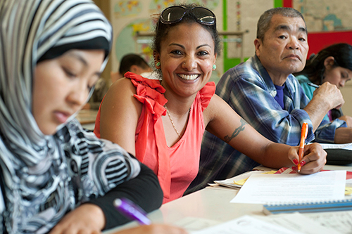 Adult students writing at a table