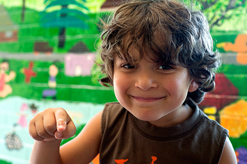 Child smiling and pointing at the camera