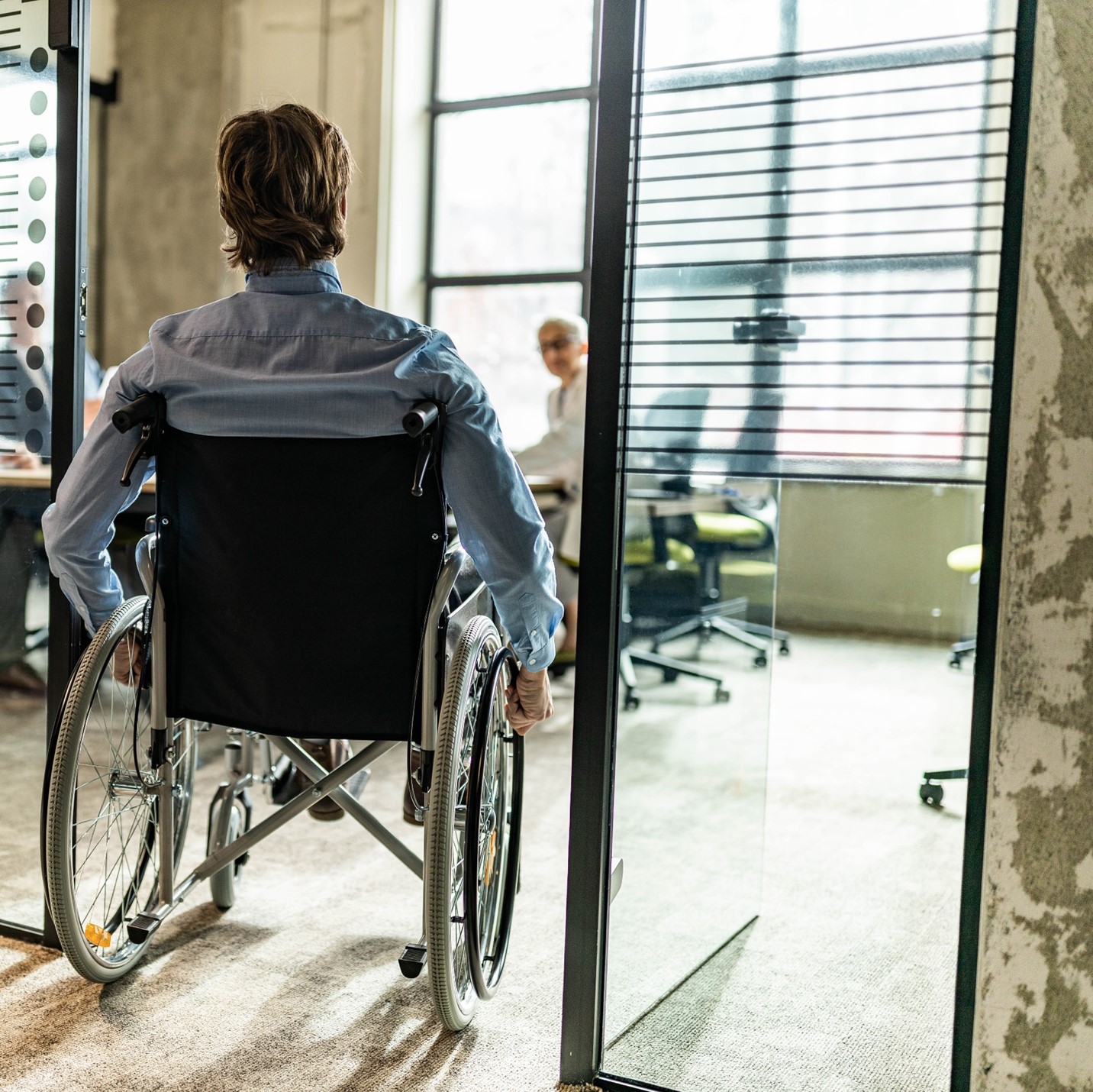 Wheelchair user looking at a glass wall