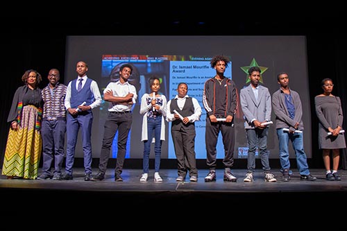 students stand on stage after receiving their awards