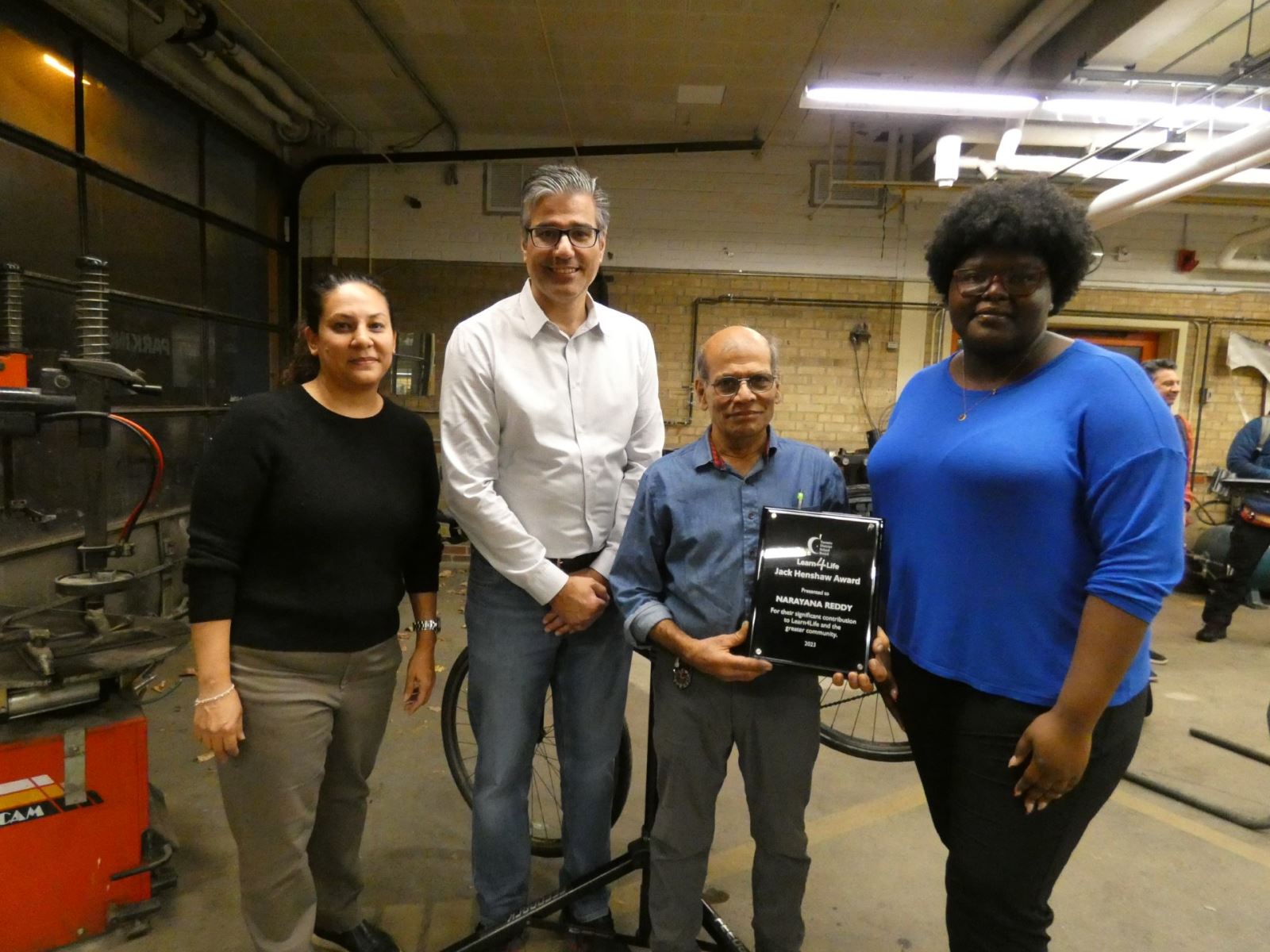 2023 Jack Henshaw Award Winner Narayana Reddy holding a plaque beside Learn4Life administrators