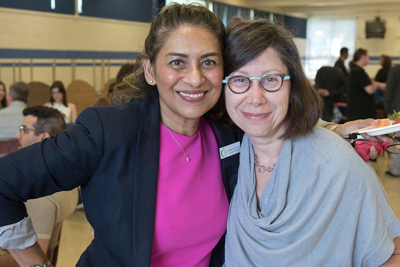 Two staff members smile and pose  