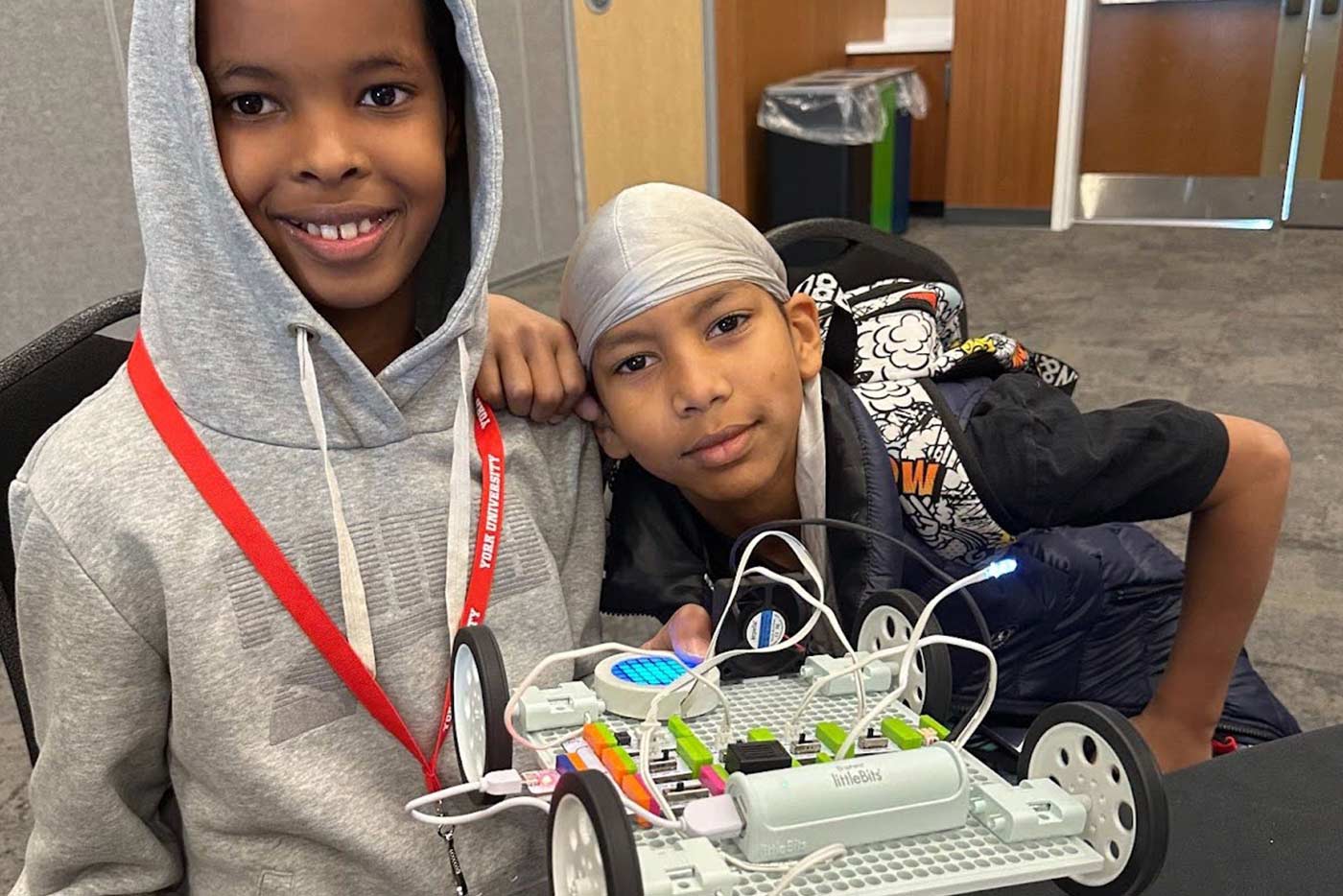 Two students hold up robotics creation