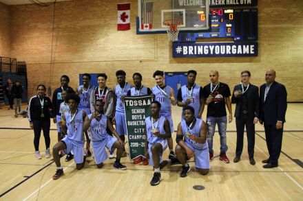 The Kipling Collegiate boys basketball team posing with their championship medals and banner.