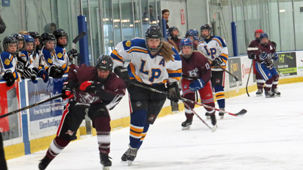 A girl is playing Hockey with other boys